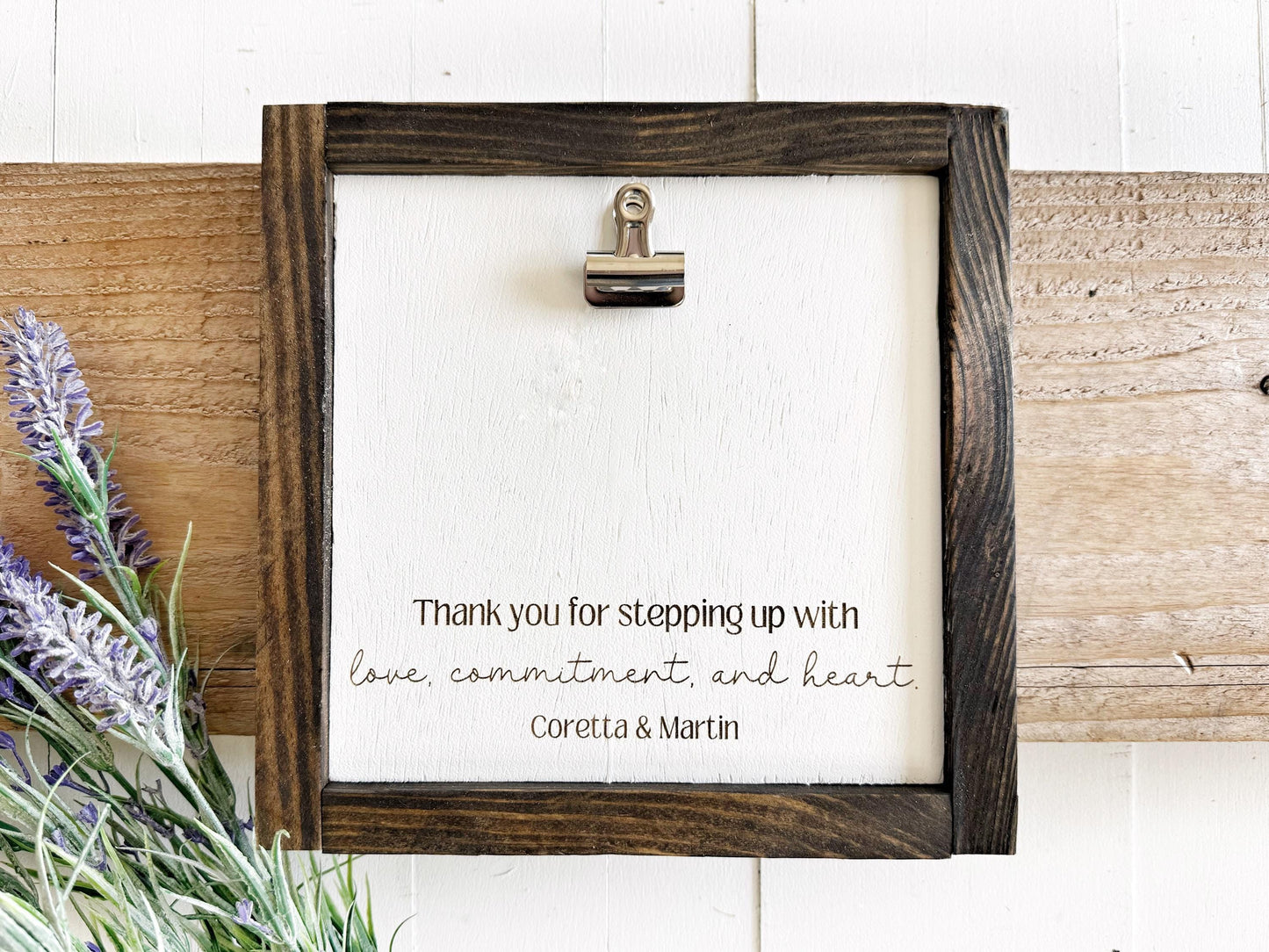 a wooden frame with a white background, and there is a silver clip on the top left corner. The frame has a handwritten message that reads, "Thank you for stepping up with love, commitment, and heart. Coretta & Martin".