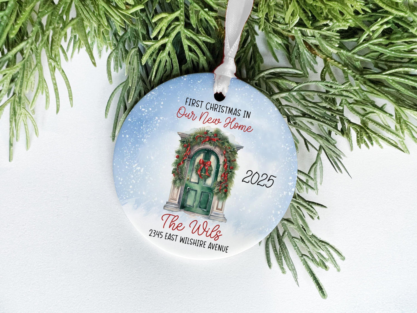 A Christmas ornament with a wreath and a door, hanging on a branch of a pine tree.