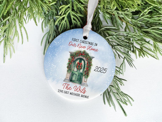 A Christmas ornament with a wreath and a door, hanging on a branch of a pine tree.