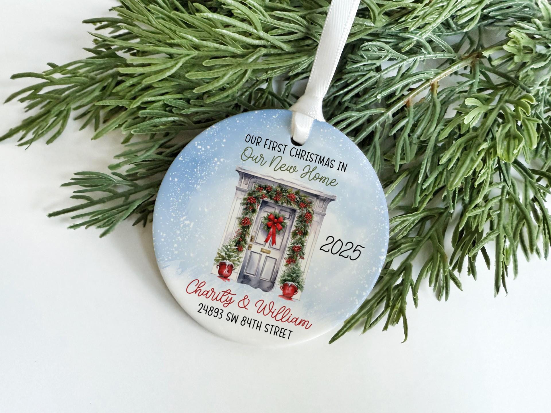 A Christmas ornament with a wreath and a door, hanging on a branch of a pine tree.