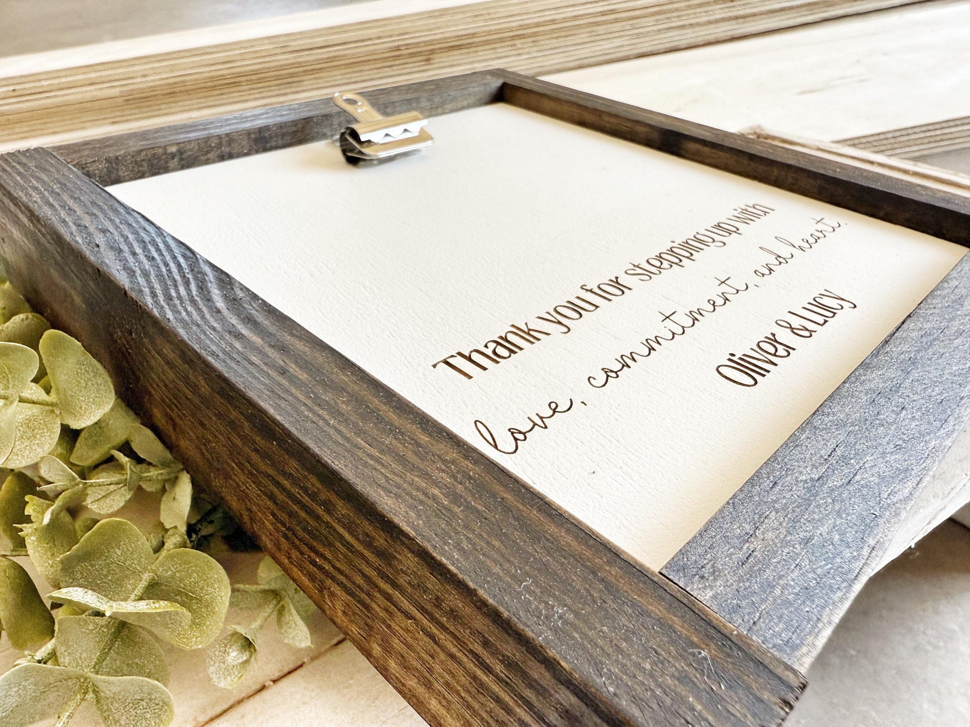 a wooden frame with a white canvas inside, displaying a heartfelt message.