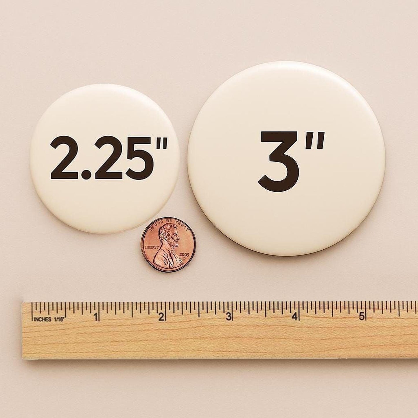 a ruler and two circular buttons, one labeled "2.25" and the other labeled "3.25", placed next to a penny for scale.