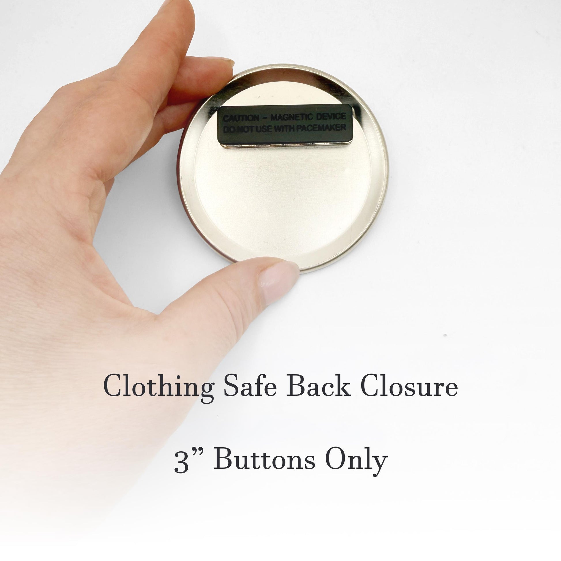 A hand holding a small, round, metal object with a warning label on it.