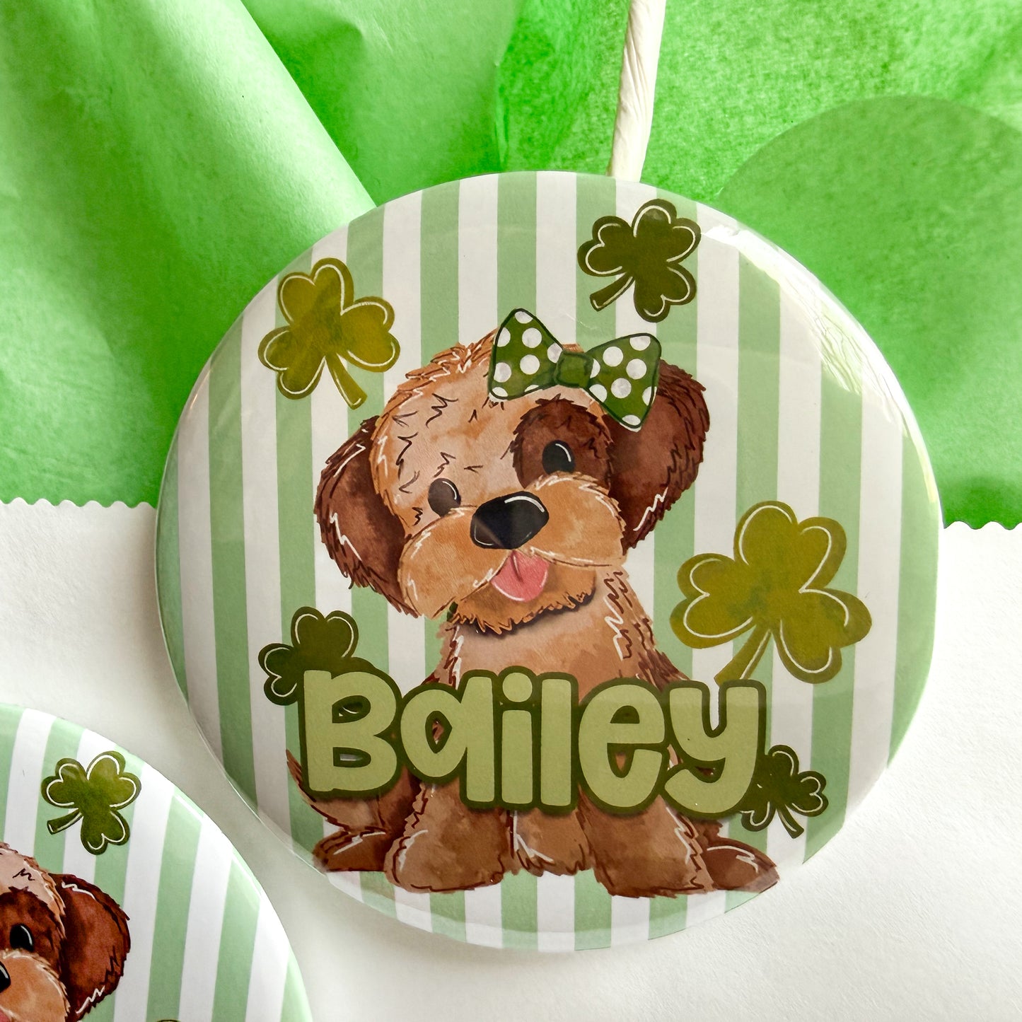 A round pin with a cartoon dog wearing a green bow and surrounded by shamrocks, with the name "Biley" written below.