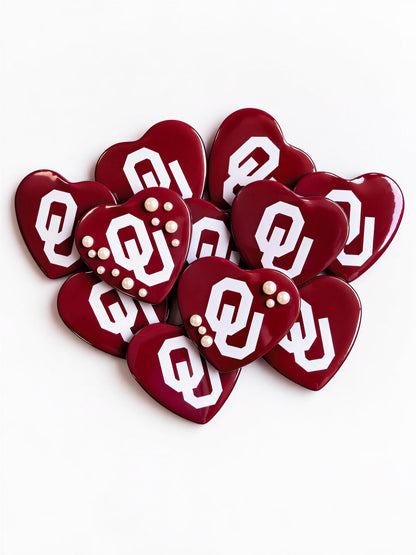 A group of red heart-shaped objects with white text and symbols, likely representing the Oklahoma State University (OSU) logo.
