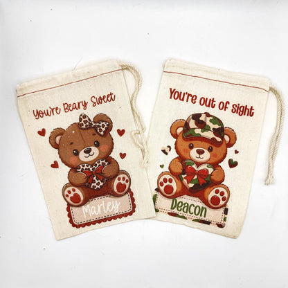 two white fabric bags with teddy bear designs and personalized names printed on them.