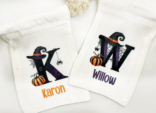 two white towels with personalized monogrammed letters and Halloween-themed illustrations.