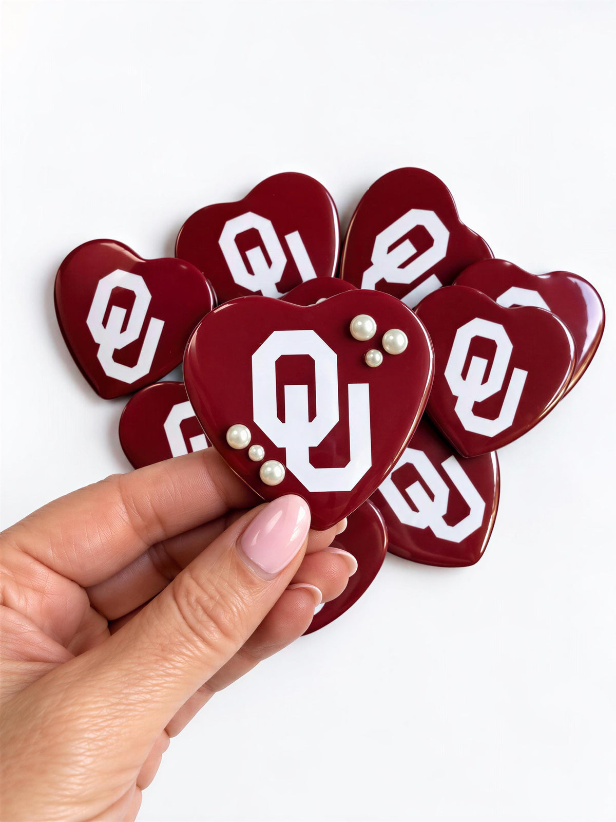 A hand holding a heart-shaped object with the letters "QJ" on it, surrounded by other similar heart-shaped objects.
