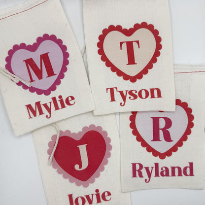 four white fabric bags with personalized names printed on them.