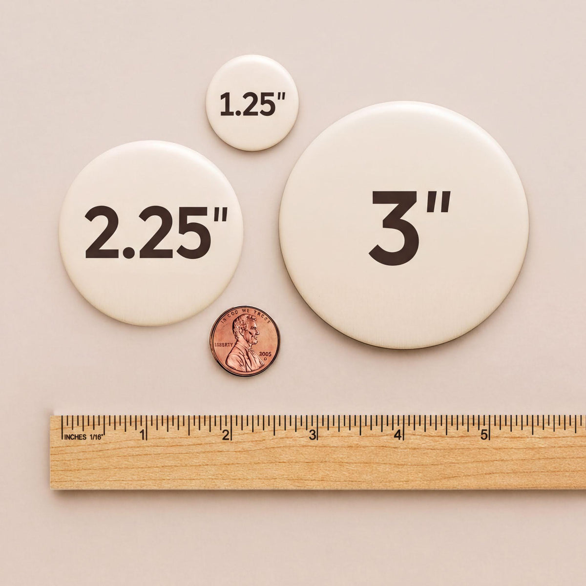 a collection of three circular objects, each with a different size indicated by the text "2.25", "3", and "1.25" printed on them. A ruler is placed next to the objects, and a penny is also visible in the image.