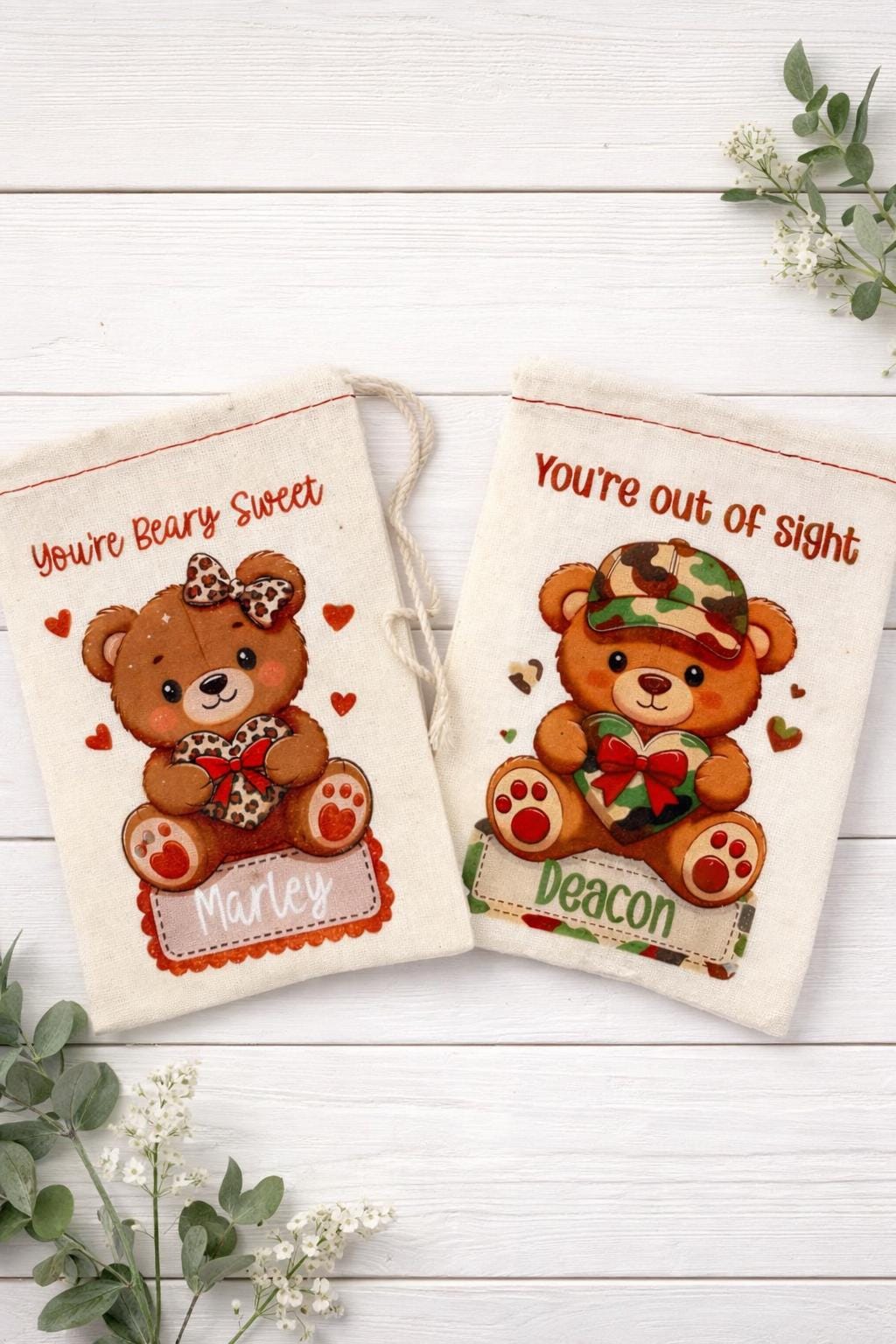 two white fabric bags with teddy bear illustrations and personalized names printed on them.