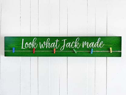 A green wooden sign with the text "Look what Jack made" written on it, hanging on a white wall.
