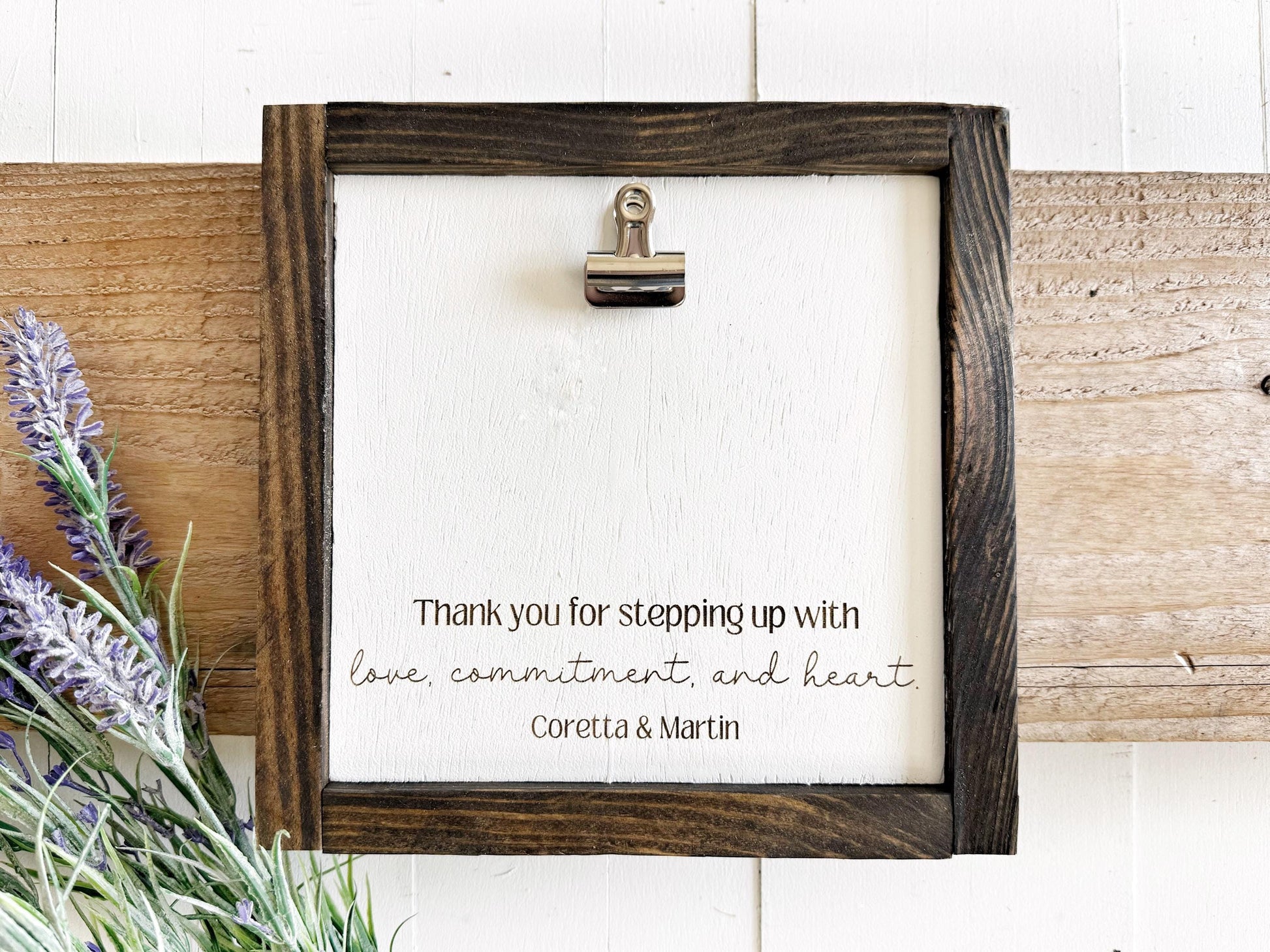 a wooden frame with a white background, and there is a silver clip on the top left corner. The frame has a handwritten message that reads, "Thank you for stepping up with love, commitment, and heart. Coretta & Martin".