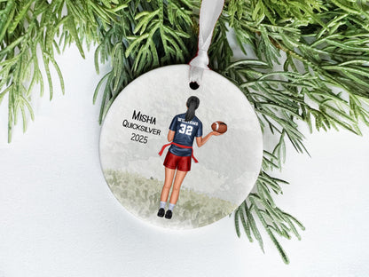 A white ornament with a picture of a person holding a football, surrounded by greenery.