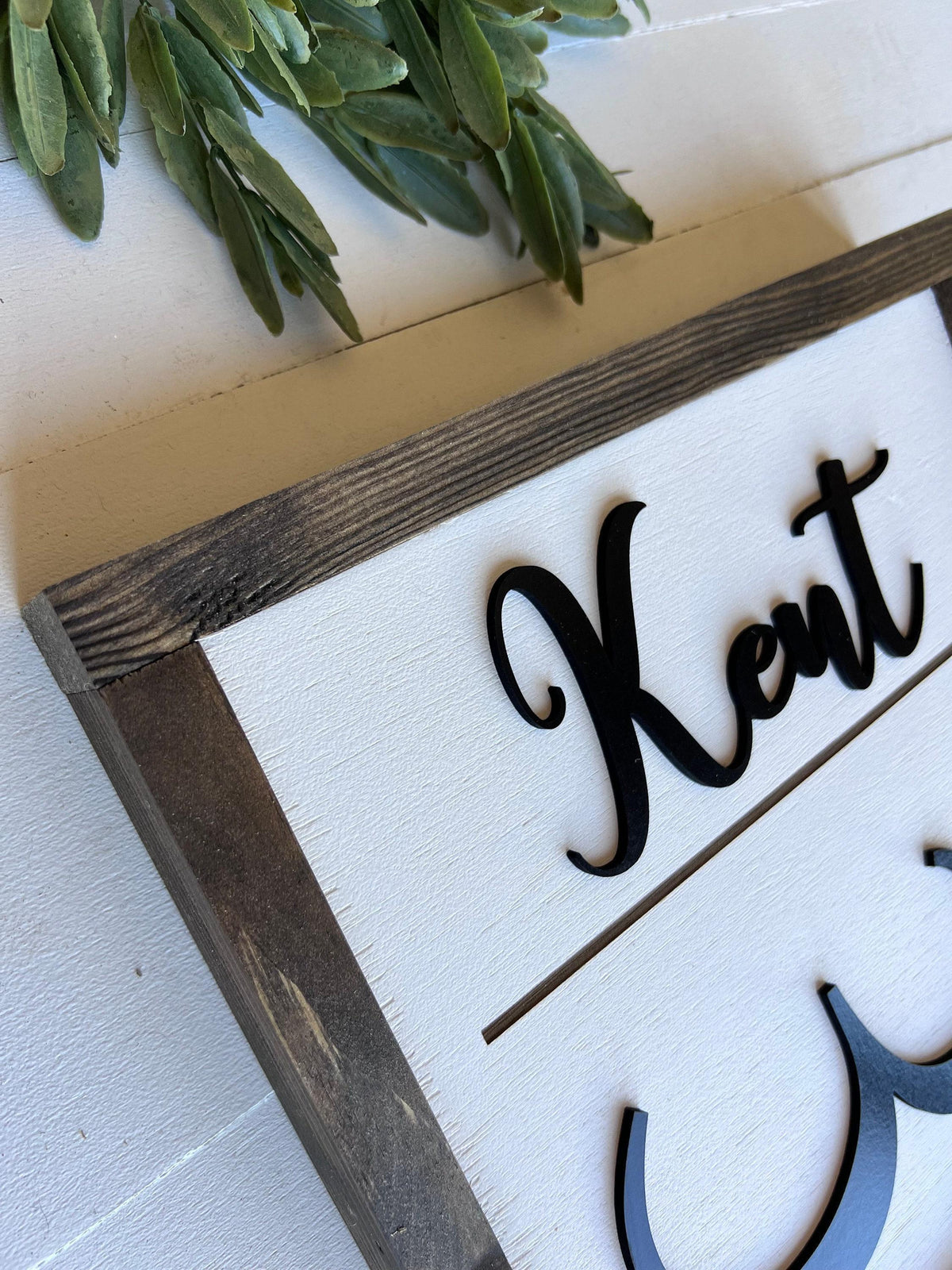 a wooden frame with the name 'Kent' written on it in a cursive font.