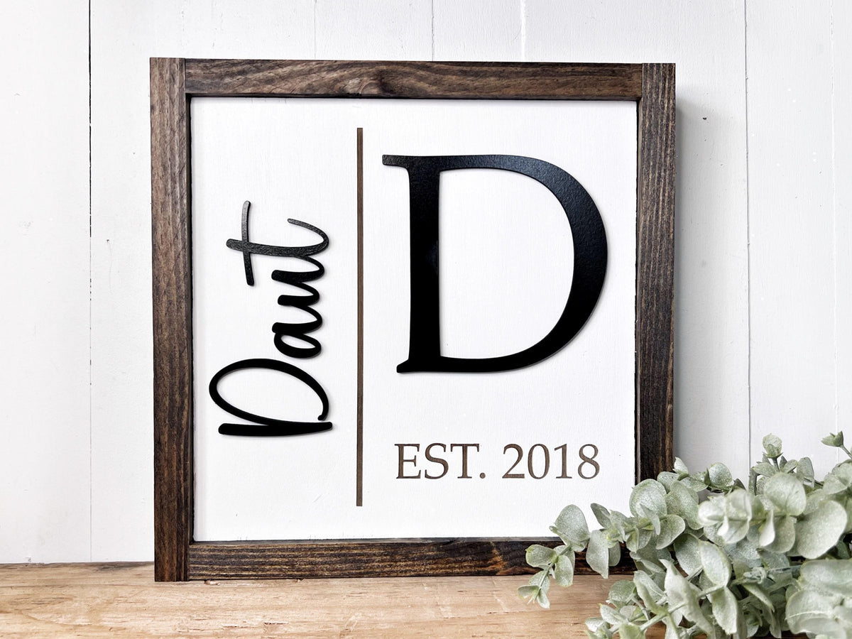 A wooden framed sign displaying the initials "D.D." and the year "EST. 2018" in a white background.